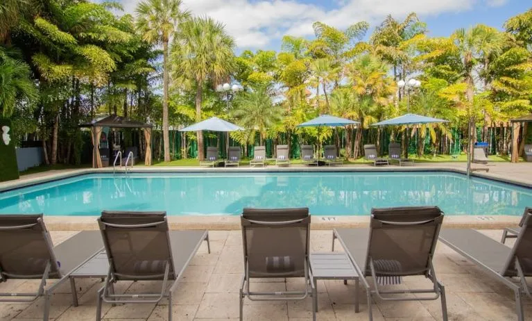 Outdoor pool with loungers at Regency Miami Airport By Sonesta.