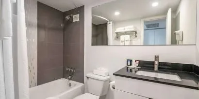 Guest bathroom with shower and bath at Ramada Plaza Marco Polo Beach Resort.