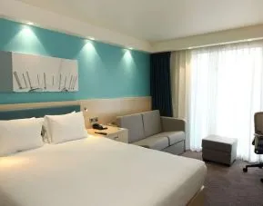 Day use room with king bed, work desk and sofa at the Hampton by Hilton London Docklands.