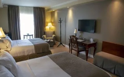 Twin day use room with TV, work desk and lounge seating at Hotel Brossard.