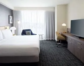 Day use room with king bed, TV, work desk and lounge area at Hilton Garden Inn Montreal Midtown.