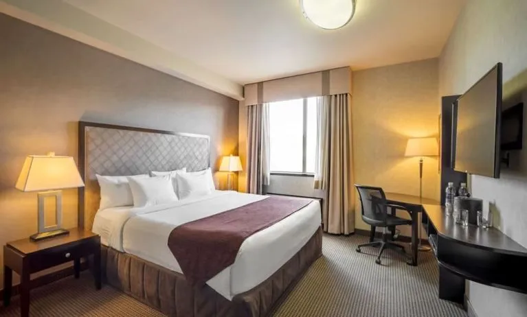 Standard day use room with TV, work desk and private bathroom at Acclaim Hotel Calgary Airport.