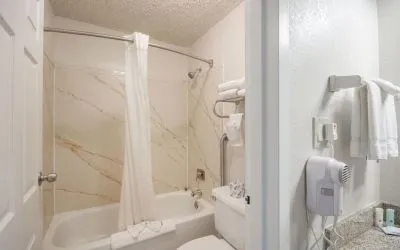 Guest bathroom with shower and tub at Coratel Plus Suites Wichita West Airport.