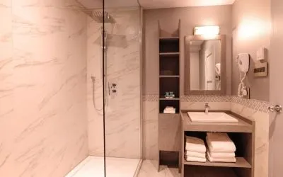 Guest bathroom with shower and free toiletries at Le Chabrol Hotel Et Suites.