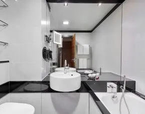 Private guest bathroom with separate shower and tub at Leonardo Royal Hotel London Tower Bridge.