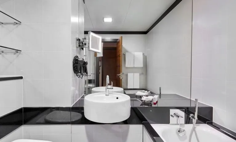 Private guest bathroom with separate shower and tub at Leonardo Royal Hotel London Tower Bridge.