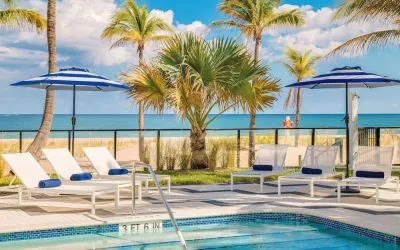 Refreshing outdoor pool surrounded by sun loungers with a view of the ocean at Plunge Beach Resort.
