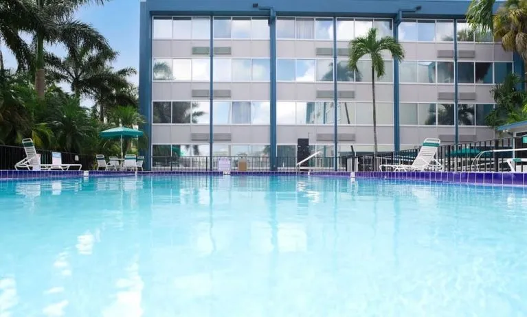 Relaxing outdoor pool with lounge area at EnVision Hotel Miami International Airport.