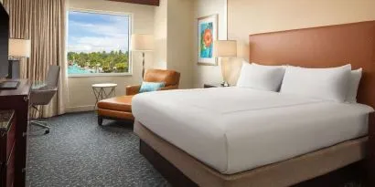 King room with TV, work desk, sofa and a great pool view at Hilton Orlando.