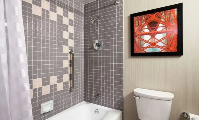 Guest bathroom with shower and tub at Embassy Suites By Hilton San Francisco Airport Waterfront.