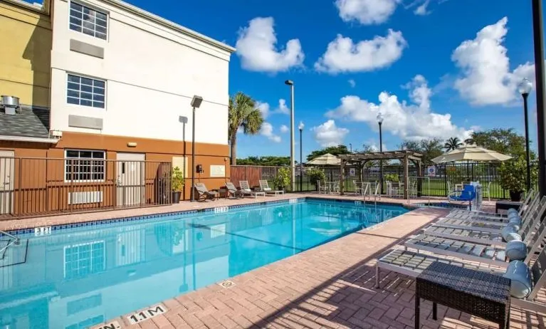 Outdoor pool with lounge chairs at Sonesta Simply Suites Miami Airport Doral.