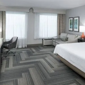 Spacious king bed room with work desk and sofa at Hampton Inn & Suites By Hilton Atlanta Perimeter Dunwoody.
