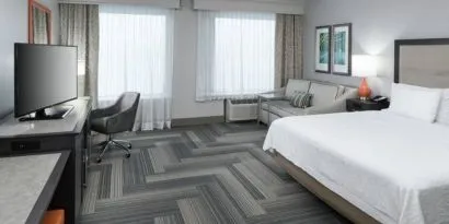 Spacious king bed room with work desk and sofa at Hampton Inn & Suites By Hilton Atlanta Perimeter Dunwoody.
