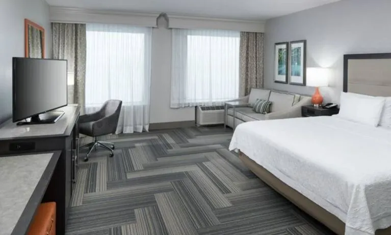 Spacious king bed room with work desk and sofa at Hampton Inn & Suites By Hilton Atlanta Perimeter Dunwoody.
