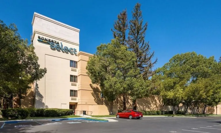 Hotel exterior and parking area at Sonesta Select San Jose Airport.