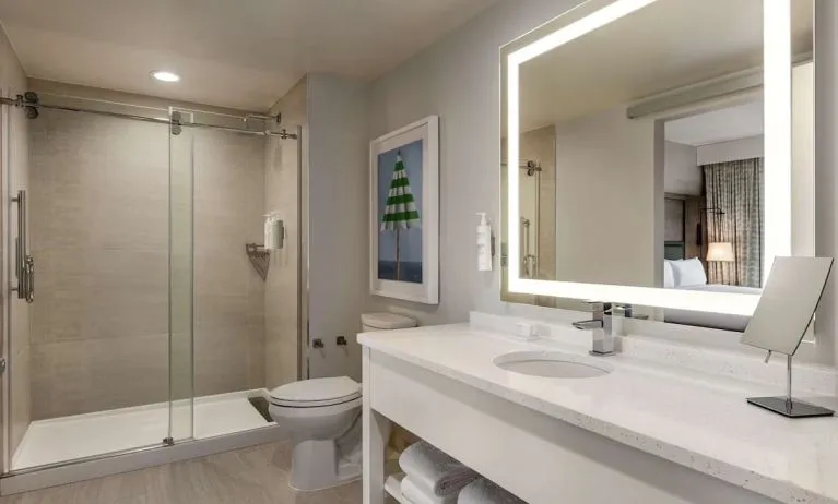 Private guest bathroom with shower and free toiletries at Embassy Suites By Hilton Panama City Beach Resort.
