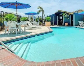 Outdoor pool with lounge chairs at Travelodge LAX By Wyndham.
