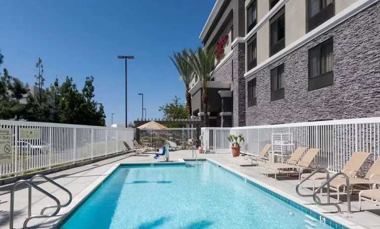 Outdoor pool with lounge chairs at Hampton Inn Los Angeles-Orange County-Cypress.