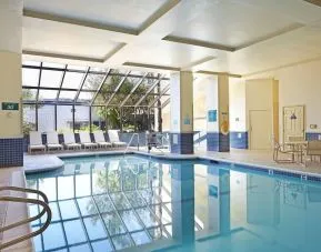 Relaxing indoor pool with lounge chairs at Embassy Suites By Hilton Los Angeles-Intl Airport North.