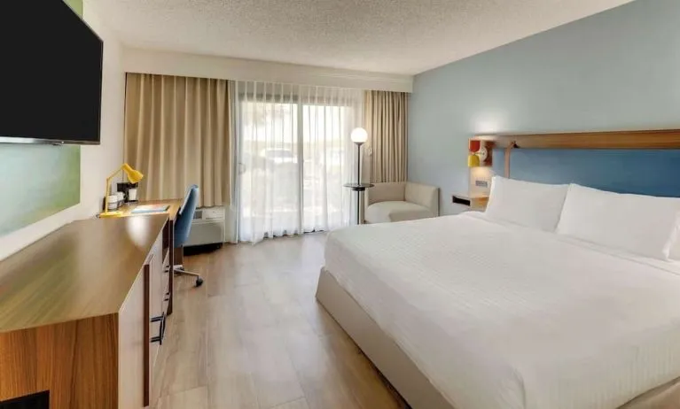Day use room with king bed, work desk, sofa, TV screen and floor to ceiling window at Sonesta Select Scottsdale At Mayo Clinic Campus.