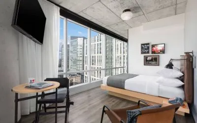 Delux king room with work desk and a view of the city at Moxy Boston Downtown.