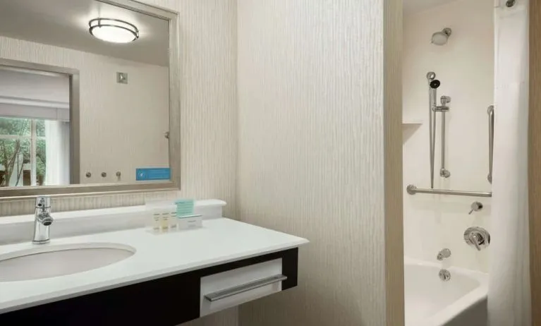 Private guest bathroom with combined shower and tub at Hampton Inn & Suites Rosemont Chicago O'Hare.