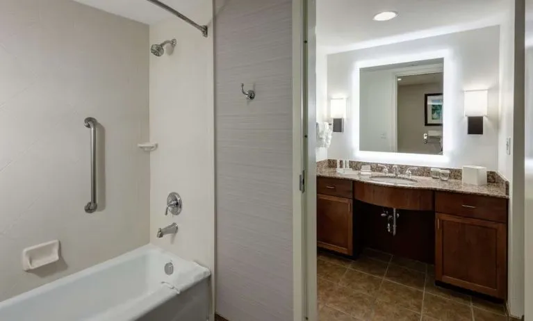 Private guest bathroom with combined shower and tub at Homewood Suites By Hilton Denton.