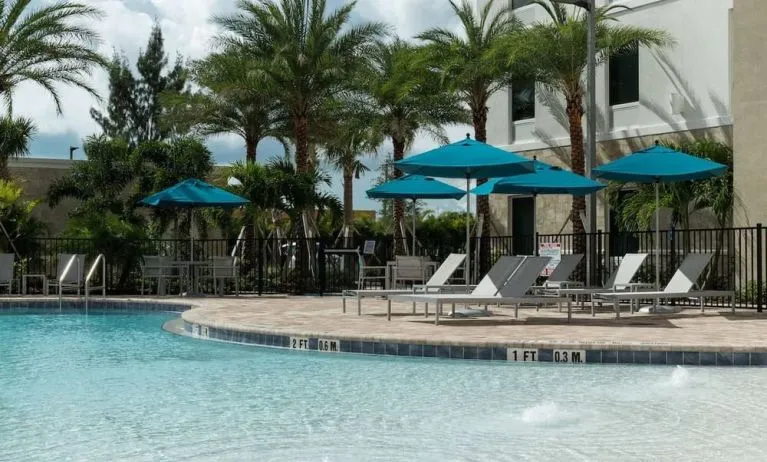 Outdoor pool with lounge chairs at Home2 Suites By Hilton Cape Canaveral Cruise Port.