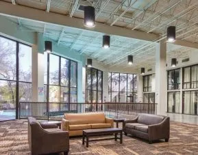 Comfortable lobby and coworking space with lots of natural light at Red Roof PLUS+ & Suites Houston - IAH Airport SW.