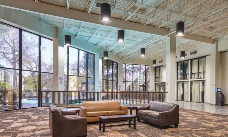 Comfortable lobby and coworking space with lots of natural light at Red Roof PLUS+ & Suites Houston - IAH Airport SW.