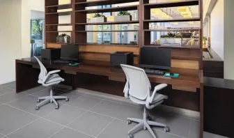 Business center with computers, printer and ergonomic chairs at Element Miami International Airport.