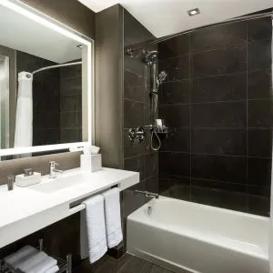 Private guest bathroom with combined shower and tub at AC Hotel New York Times Square.