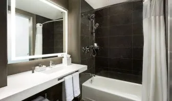 Private guest bathroom with combined shower and tub at AC Hotel New York Times Square.