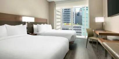 Day use twin room with workspace, floor to ceiling window and private bathroom at AC Hotel New York Times Square.