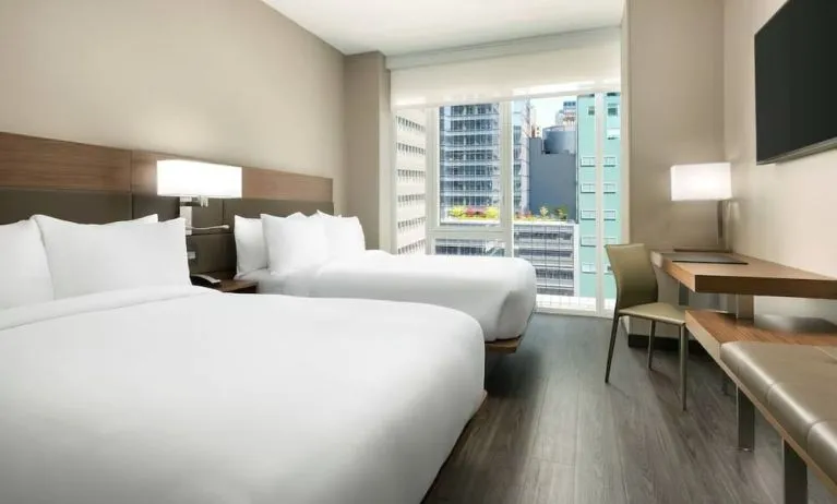 Day use twin room with workspace, floor to ceiling window and private bathroom at AC Hotel New York Times Square.