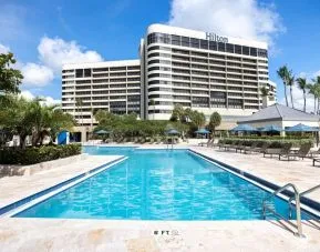 Outdoor pool with lounge seating at Hilton Miami Airport Blue Lagoon.