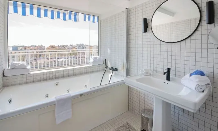 Guest bathroom with tub and natural light at Splendid Hotel & Spa Nice.