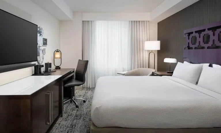Delux king room with TV, work desk, and natural light at Courtyard San Diego Downtown.