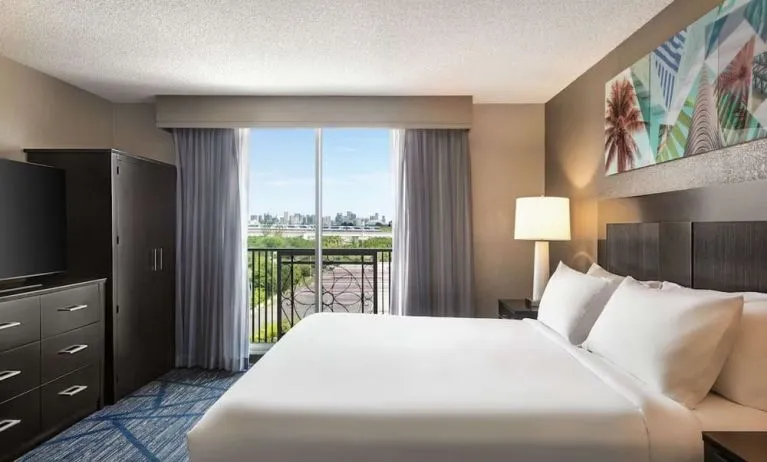Day use room with king bed, balcony, TV screen and private bathroom at Embassy Suites By Hilton Miami - International Airport.