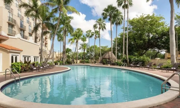 Beautiful outdoor pool with lounge chairs at Embassy Suites By Hilton Miami - International Airport.