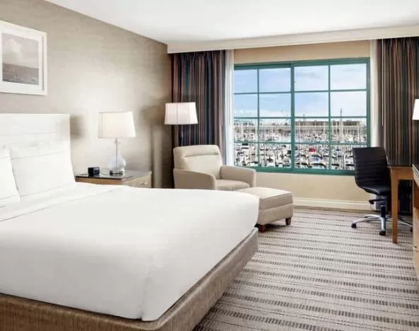 Bright queen suite hotel room with workspace and prime view of San Pedro port and marina.