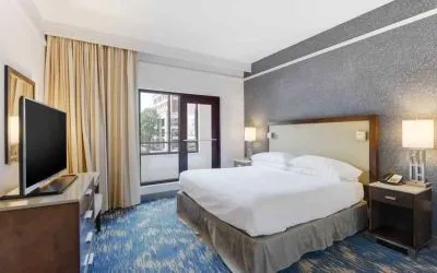 King size bed, large window and TV screen in a king room at the Embassy Suites by Hilton Alexandria-Old Town.