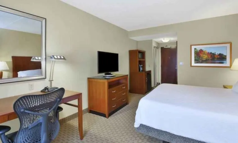 King size bed, desk and TV screen in a hotel room at the Hilton Garden Inn Clarksburg.