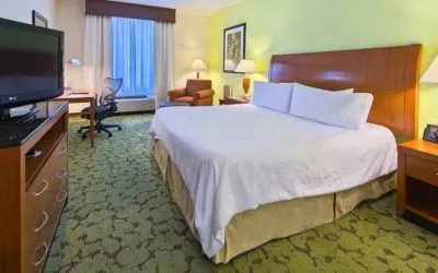 King size bed, TV screen and desk in a hotel room at the Hilton Garden Inn Tallahassee Central.
