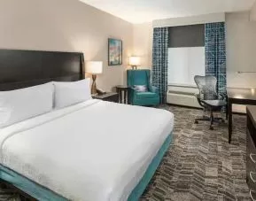 Comfortable hotel guestroom with king size bed and working station at the Hilton Garden Inn Silver Spring White Oak.