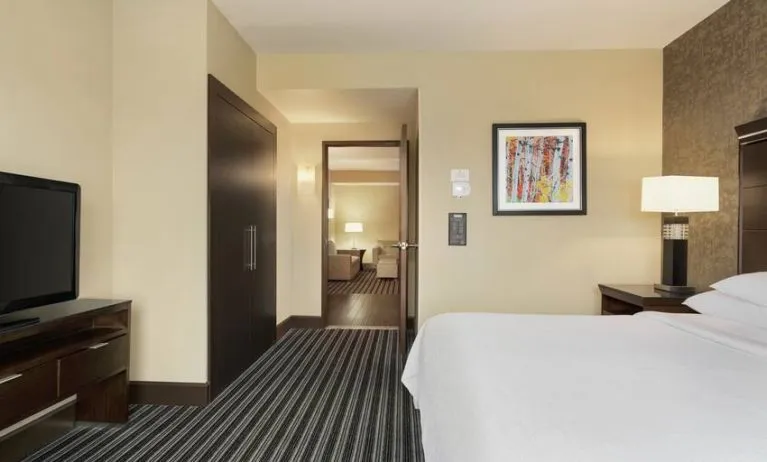 King size bed and TV screen in a king bedroom at the Embassy Suites by Hilton Salt Lake City West Valley.