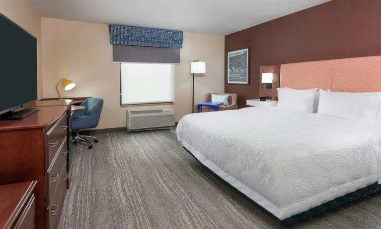 Spacious king bedroom with desk and TV screen at the Hampton Inn Springfield South Enfield.