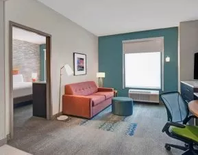 Living room with working station in a hotel room at the Home2 Suites by Hilton Houston Medical Center.