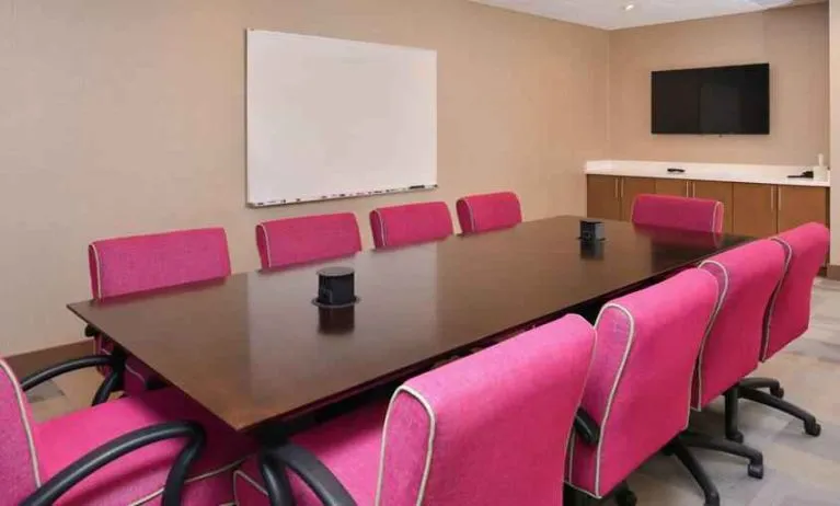 Small meeting room with pink chairs at the Hampton Inn & Suites St. Paul Oakdale/Woodbury by Hilton.