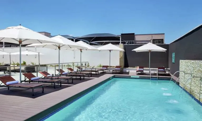 Narrow rectangular pool with fountains coming out of side wall, abundant lounge chairs for sunbathing.